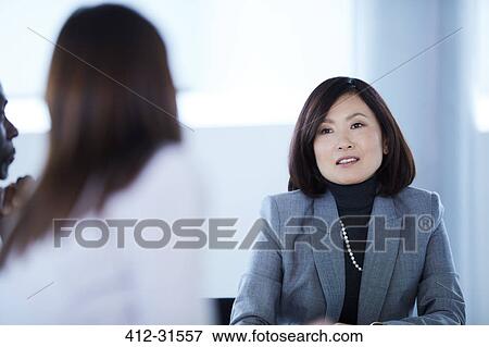 Stock Photo - Businesswomen talking in meeting. Fotosearch