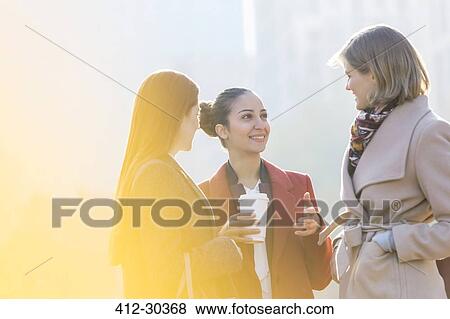 Businesswomen with coffee talking outdoors View Large Photo Image Stock Photo - Businesswomen with coffee talking outdoors. Fotosearch