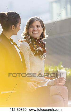 Stock Image - Businesswomen with digital tablet and coffee outdoors. Fotosearch