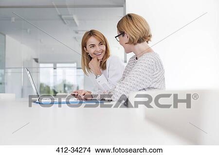 Businesswomen working at laptop in conference room View Large Photo Image Picture - Businesswomen working at laptop in conference room. Fotosearch