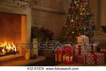 Stock Photography - Christmas tree and gifts near fireplace in living room. Fotosearch