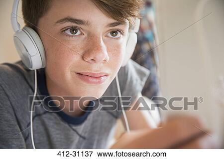 Close up boy with headphones listening to music on digital tablet View Large Photo Image Stock Photo - Close up boy with headphones listening to music on digital tablet. Fotosearch