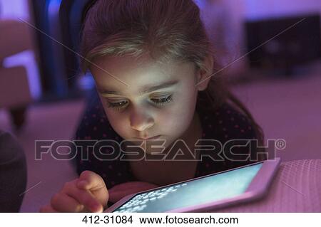 Close up girl playing game on digital tablet in the dark View Large Photo Image Picture - Close up girl playing game on digital tablet in the dark. Fotosearch