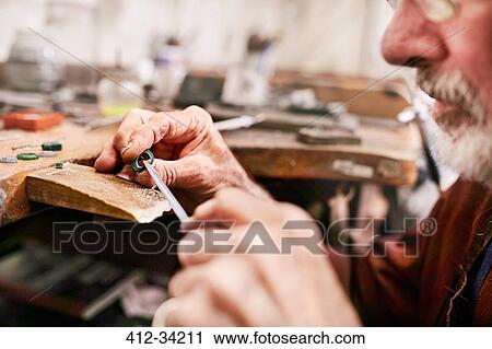 Stock Image - Close up male jeweler making jewelry in workshop. Fotosearch
