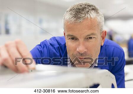 Stock Photograph - Close up of worker examining piece in steel factory. Fotosearch