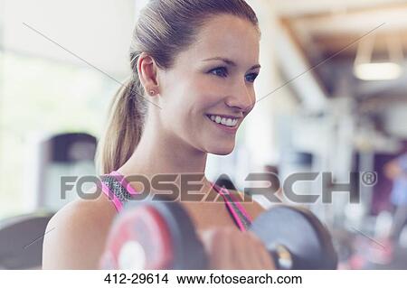Close up smiling woman doing dumbbell biceps curls at gym View Large Photo Image Picture - Close up smiling woman doing dumbbell biceps curls at gym. Fotosearch