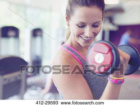 Close up smiling woman doing dumbbell biceps curls at gym View Large Photo Image Stock Image - Close up smiling woman doing dumbbell biceps curls at gym. Fotosearch