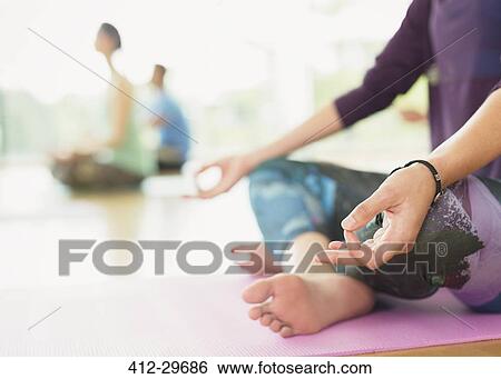 Stock Photograph - Close up woman in lotus position practicing gyan mudra. Fotosearch