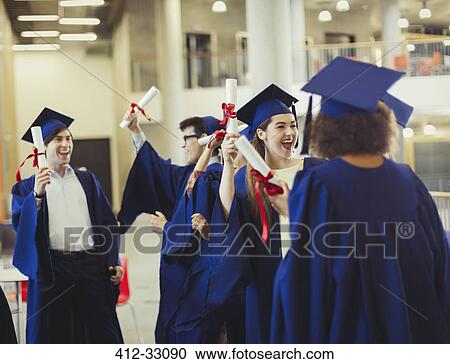 Stock Image - College graduates in cap and gown holding diplomas. Fotosearch