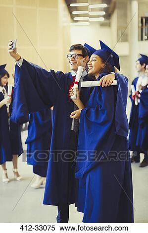 College graduates in cap and gown with diplomas taking selfie View Large Photo Image Stock Photography - College graduates in cap and gown with diplomas taking selfie. Fotosearch