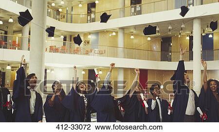 Stock Image - College graduates throwing cap. Fotosearch