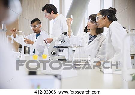 Stock Photograph - College students conducting scientific experiment in science laboratory classroom. Fotosearch