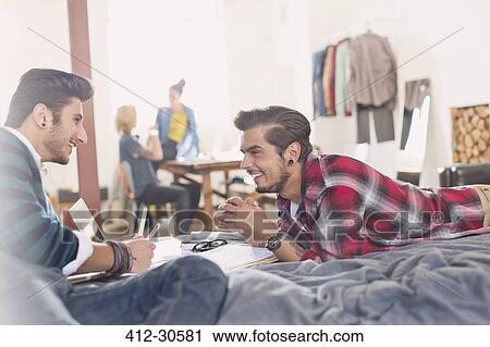 Stock Image - College students studying on bed in apartment. Fotosearch