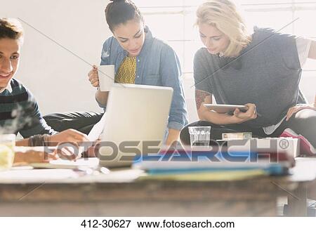 Stock Photo - College students studying with coffee, laptop and digital tablet. Fotosearch