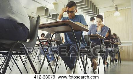Stock Photo - College students taking test at desk in classroom. Fotosearch
