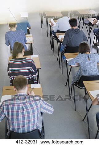 Stock Image - College students taking test at desks in classroom. Fotosearch