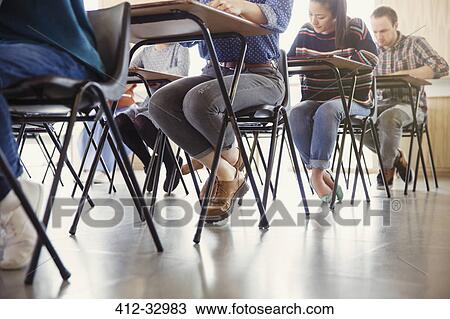 Stock Image - College students taking test at desks in classroom. Fotosearch