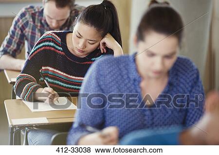 Stock Photo - College students taking test at desks in classroom. Fotosearch
