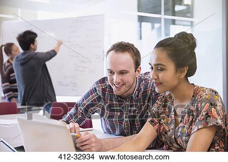 Picture - College students using laptop and digital tablet in classroom. Fotosearch