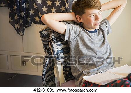 Stock Photography - Confident boy doing homework with hands behind head. Fotosearch
