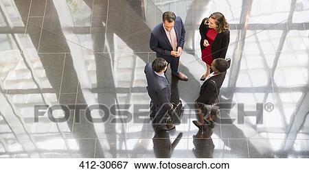Stock Photo - Corporate business people talking in modern office lobby. Fotosearch
