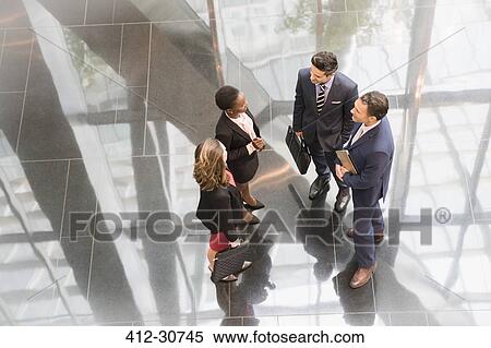 Corporate business people talking in modern office lobby View Large Photo Image Stock Photography - Corporate business people talking in modern office lobby. Fotosearch