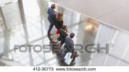 Stock Image - Corporate business people walking in a row in modern office lobby. Fotosearch