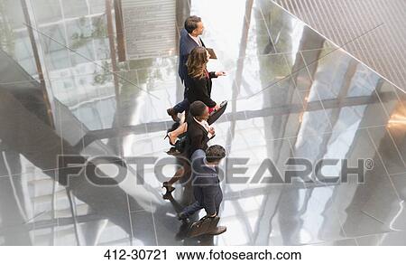 Stock Image - Corporate business people walking in modern lobby. Fotosearch