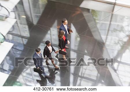Stock Image - Corporate business people walking in modern office lobby. Fotosearch