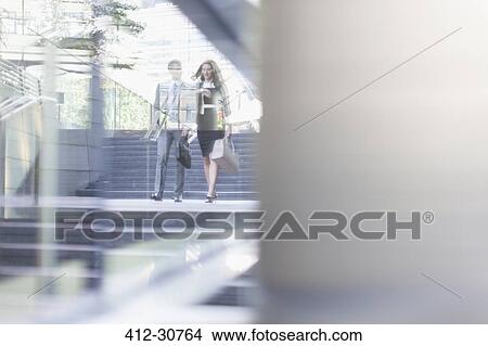 Picture - Corporate businessman and businesswoman walking outdoors. Fotosearch