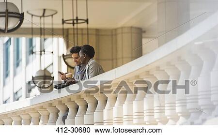 Corporate businessman and businesswoman with coffee and cell phone at railing View Large Photo Image Stock Image - Corporate businessman and businesswoman with coffee and cell phone at railing. Fotosearch