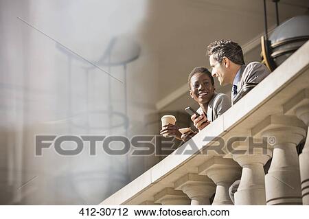 Corporate businessman and businesswoman drinking coffee at railing View Large Photo Image Stock Image - Corporate businessman and businesswoman drinking coffee at railing. Fotosearch