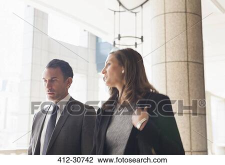 Corporate businessman and businesswoman talking and walking outdoors View Large Photo Image Stock Image - Corporate businessman and businesswoman talking and walking outdoors. Fotosearch
