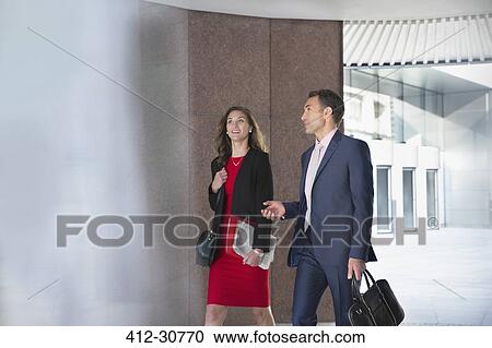 Corporate businessman and businesswoman talking and walking outdoors View Large Photo Image Stock Image - Corporate businessman and businesswoman talking and walking outdoors. Fotosearch