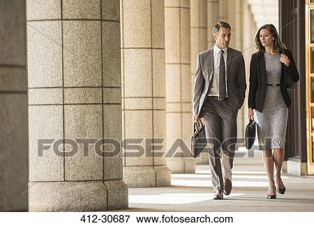 Stock Photo - Corporate businessman and businesswoman walking and talking in cloister. Fotosearch
