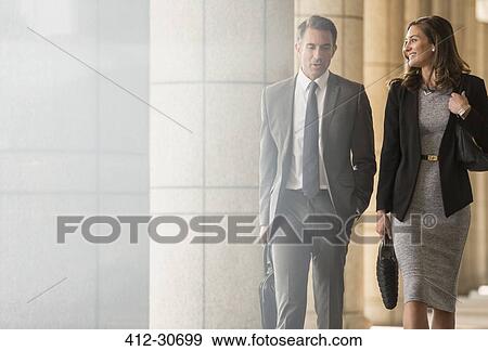 Corporate businessman and businesswoman walking and talking in cloister View Large Photo Image Stock Photo - Corporate businessman and businesswoman walking and talking in cloister. Fotosearch