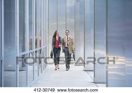 Corporate businessman and businesswoman walking along modern building View Large Photo Image Stock Photo - Corporate businessman and businesswoman walking along modern building. Fotosearch