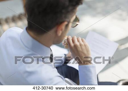 Corporate businessman eating lunch and reading paperwork View Large Photo Image Stock Image - Corporate businessman eating lunch and reading paperwork. Fotosearch