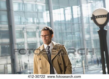 Corporate businessman in trench coat looking away View Large Photo Image Stock Image - Corporate businessman in trench coat looking away. Fotosearch