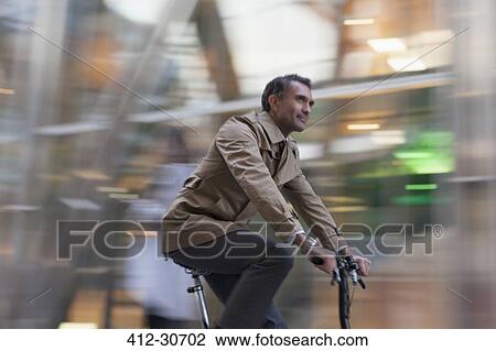 Stock Image - Corporate businessman riding bicycle. Fotosearch