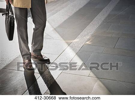 Stock Photo - Corporate businessman standing on sunny pavement. Fotosearch