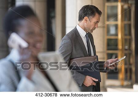 Stock Photo - Corporate businessman using digital tablet outdoors. Fotosearch