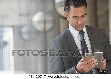 Corporate businessman using digital tablet outdoors View Large Photo Image Stock Photo - Corporate businessman using digital tablet outdoors. Fotosearch
