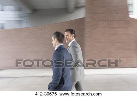 Stock Photography - Corporate businessmen walking outside building. Fotosearch
