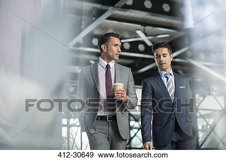 Stock Photo - Corporate businessmen walking with coffee. Fotosearch
