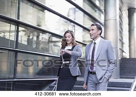 Corporate businesswoman checking wristwatch outside modern building View Large Photo Image Stock Image - Corporate businesswoman checking wristwatch outside modern building. Fotosearch