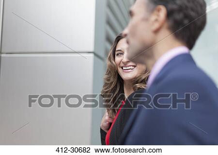 Stock Image - Corporate businesswoman smiling at businessman. Fotosearch