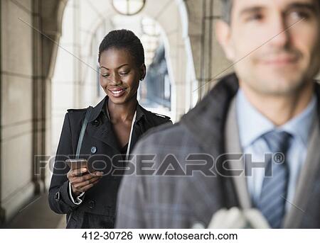 Corporate businesswoman texting with cell phone in cloister View Large Photo Image Stock Photograph - Corporate businesswoman texting with cell phone in cloister. Fotosearch