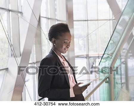 Corporate businesswoman using digital tablet in modern office lobby View Large Photo Image Picture - Corporate businesswoman using digital tablet in modern office lobby. Fotosearch