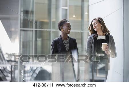 Corporate businesswomen with coffee talking and walking View Large Photo Image Stock Image - Corporate businesswomen with coffee talking and walking. Fotosearch